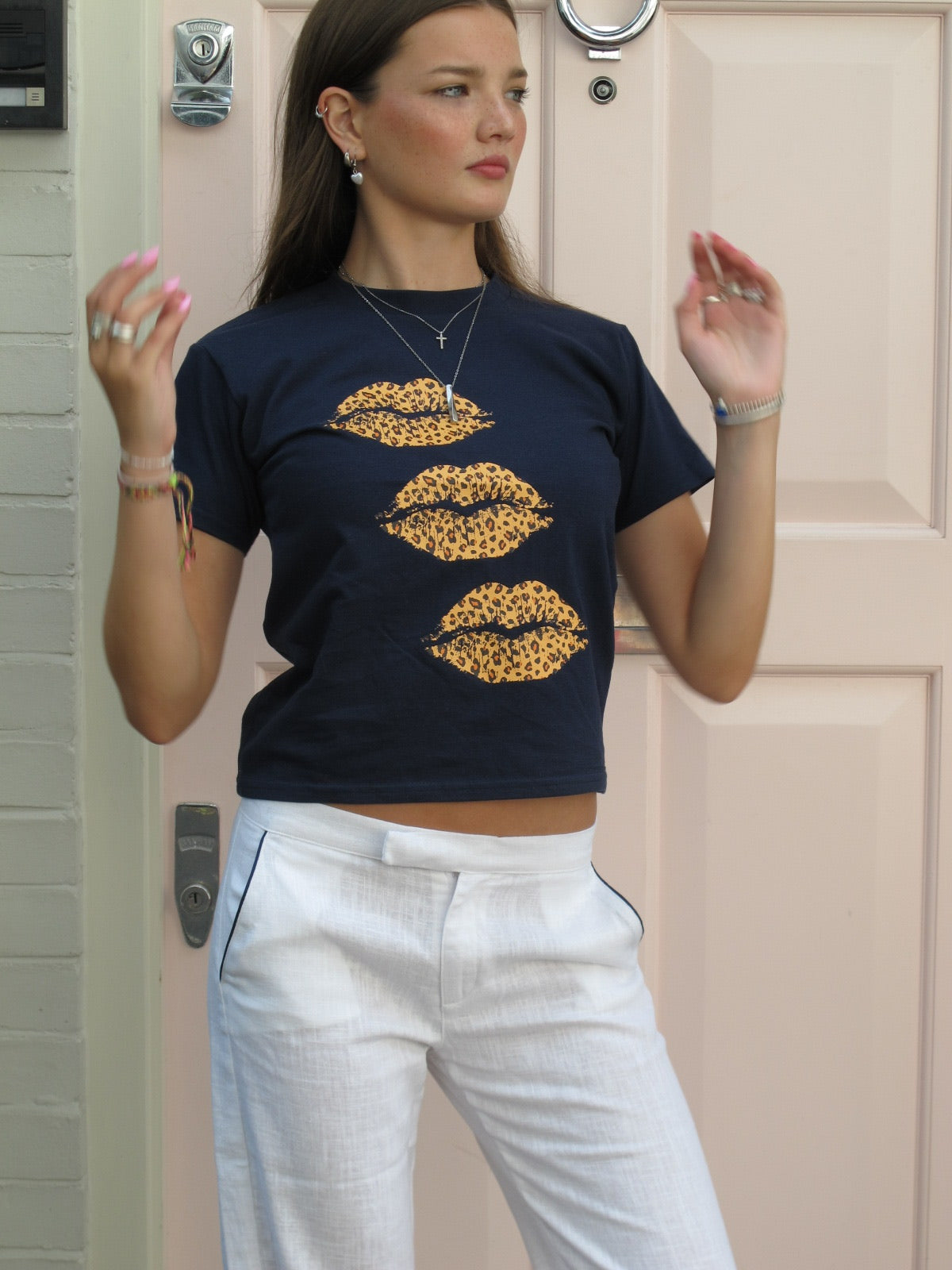 White linen trousers with navy piping along the pockets, styled in the summer with a T-shirt, worn by a woman 