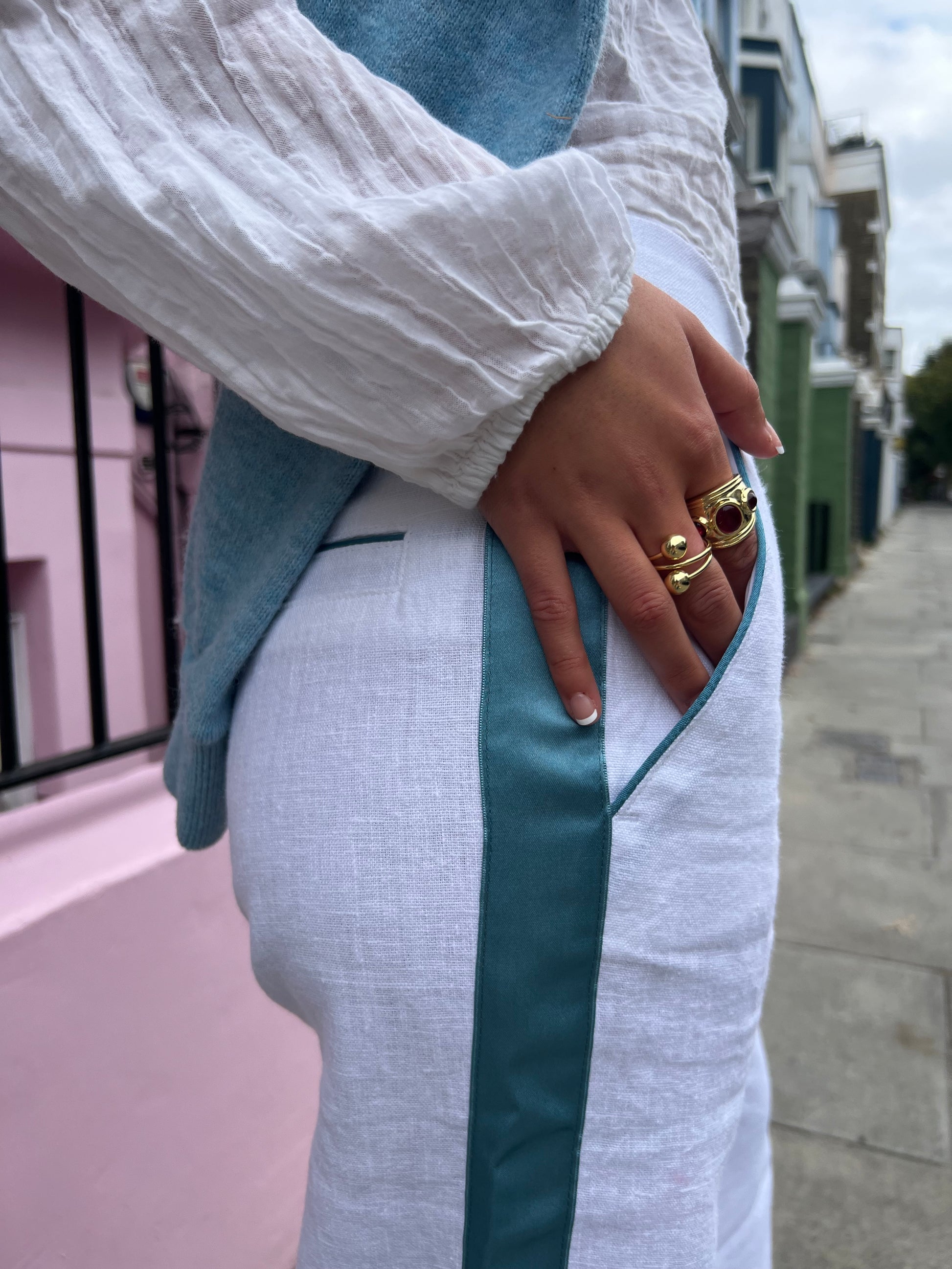 Close-up of a person wearing teal and white linen trousers with a focus on the fabric and fit.